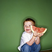 Kleiner Junge hält angebissene Wassermelonenspalte