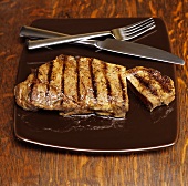 Grilled Steak on a Plate with Fork and Knife; Sliced