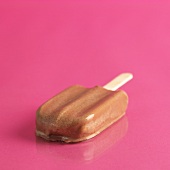 A chocolate ice lolly lying on a pink surface