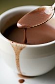 Heiße Schokolade tropft vom Löffel in Tasse