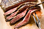 Sliced Steak on Cutting Board; Carving Utensils