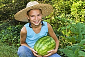 Young Girl Holding a Fresh Picked Watermelon in a Garden