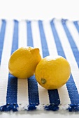 Zwei Zitronen auf blau-weiss gestreiftem Tuch