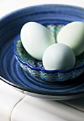 Three blue eggs in a ceramic bowl