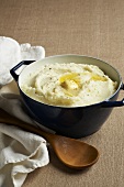 Pot of Mashed Potatoes with Melting Butter; Wooden Spoon