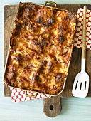 Rustic Lasagna in a Pan on Cutting Board; Spatula; From Above