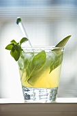 Glass of Iced Tea with Fresh Herbs and Cucumber Spear