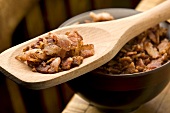Knusprige Bacon Bits (Speckwürfel) in Holzschale und auf Kochlöffel