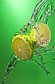 Halved Lime in Water Splashing Across Green Background