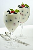 Yogurt with Raspberries and Blueberries in Two Stem Glasses; Mint Garnish