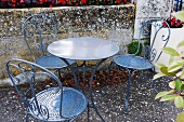 Gartentisch und Metallstühle auf herbstlicher Terrasse (Frankreich)