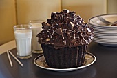 Grosser Schokoladen-Cupcake, Milchgläser und Tellerstapel