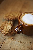 Latte with Foam; Oatmeal Raisin Cookies; On Wooden Surface