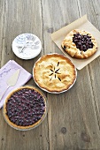 Three Pies on a Wooden Table; Blueberry, Plum and Cherry; Plates and Forks