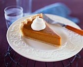 Slice of Pumpkin Pie with a Dollop of Whipped Cream on a White Plate
