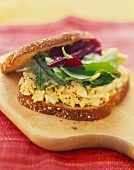 Egg Salad Sandwich with Greens on Whole Wheat Bread; On a Cutting Board