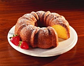 Lemon Bundt Cake with Powdered Sugar; Slice Removed; On a Platter with Strawberries