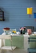 A table laid outside for spring with cake, cups and flowers