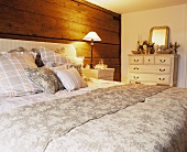 A double bed in front of a wooden wall