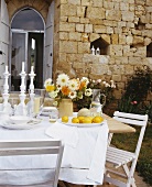 A table laid outside with a bunch of flowers and fruit