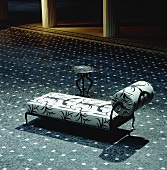 Mittig gestellte Chaiselongue in grossem Empfangsraum auf blau gemustertem Teppichboden