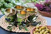 Decorated olive tins wiht twigs and a bowl of olives