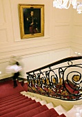 A flight of stairs in a manor house with red carpet runner