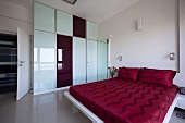 Grosszügiger Schlafraum mit Glaswand & rotbezogenem Doppelbett