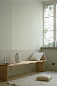 A wooden bench with books, a cushion, a lantern and a candle