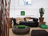 Rattan floor table in front of a black leather couch and cactus pot in a living room