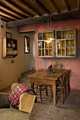 Rustic dining area in front of a red wall and under a timber beam ceiling