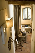 Wall lighting in a stairwell with a view of an old side table in front of a window and upholstered sofa under a window