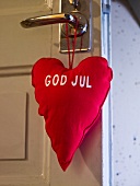 Red, heart shaped pillow hanging on a door