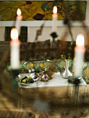 View through hanging candlesticks onto a metal table with flower vases