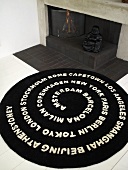 White letters on a black carpet in front of an open hearth (fireplace)