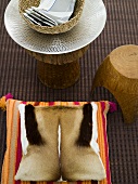 Pillows with hide covers and rustic stool with a shiny white dish