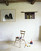 Schlichter Wohnraum mit Wurfspiel & bunten Holzwürfeln auf Holzstuhl, Wandnische als Bücherregal und Wandbild