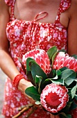 A woman holding a bunch of protea flowers