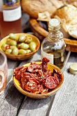 Dried tomatoes, olives and olive oil on a garden table