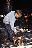 Young boy standing next to a basket next to an open fire