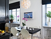 Schwarzer Esstisch mit weissen Bauhaus Stühlen und TV an der Wand