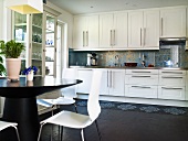 An open-plan kitchen - a view of a white fitted kitchen with stainless steel handles