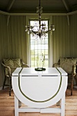 A white folding table with chairs and a chandelier in front of a window