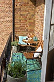 A sunny spot on a balcony in front of a brick facade with wooden chairs and pots of lavender