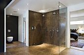 Grosser Duschbereich und WC vor schwarzer Wand im Designerbad mit Blick in Schlafraum