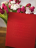 A bunch of tulips and roses and a red-bound book