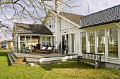 Grosses Einfamilienhaus mit weisser Holzfassade und Glasanbau auf Terrasse