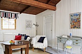 A living room in a country house with white wood panelling and a wooden ceiling