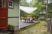 Holzhaus mit Terrasse und Sonnensegel über Gartenmöbel