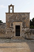 Romanische Kirche mit verwitterter Steinfassade und Glockenturm